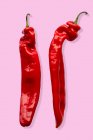 Duas fileiras de pimentas vermelhas em um fundo rosa — Fotografia de Stock