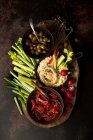 Weidenteller mit Humus, Oliven, sonnengetrockneten Tomaten und Rohkost — Stockfoto