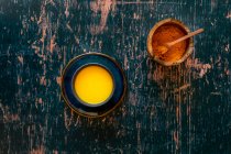 Turmeric Golden Milk on saucer and distressed green wooden surface — Stock Photo
