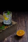 Gin and tonic with orange half on wooden surface — Stock Photo