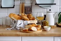 Bread variety with cream cheese, olives and white wine — Stock Photo