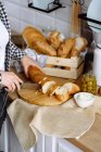 Frau in der Küche macht Sandwiches aus Baguette und Frischkäse — Stockfoto