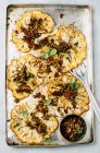 Cauliflower steaks with olive salsa on a baking tray — Stock Photo