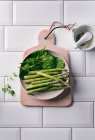 Mini asperges vertes et épinards frais dans un bol en céramique — Photo de stock