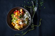 Yellow and green spaghetti with a colorful tomato and bacon sauce — Foto stock