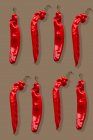 Duas fileiras de pimentas vermelhas em um fundo marrom — Fotografia de Stock