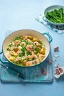 Una pentola di pesce e gamberi con patate novelle e salsa all'aglio cremosa con piselli freschi e broccoli — Foto stock