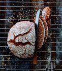 Pan redondo de espelta y semillas de sésamo, rebanado con cuchillo en estante - foto de stock