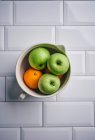Green apples and oranges in a ceramic bowl — Stock Photo