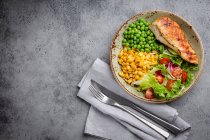 Pechuga de pollo al horno con ensalada fresca, guisantes verdes y maíz - foto de stock