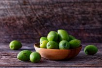 Olive verdi in una ciotola su fondo di legno — Foto stock
