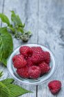 Fresh raspberries in mini  bowl with mint leaves on table — Stock Photo