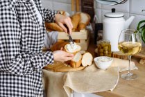 Mujer en la cocina hace sándwiches de baguette y queso crema - foto de stock