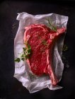 Raw steak with spices on paper — Stock Photo