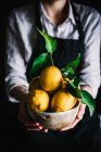 Donna che tiene ciotola con limoni — Foto stock