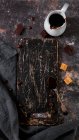 Schwarzes zerkratztes Schneidebrett neben Kaffeebohnen und dunkler Schokolade — Stockfoto