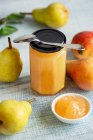 Marmellata di pere fatte in casa in vaso con cucchiaio e in ciotola e pere fresche in tavola — Foto stock