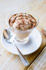 Eiskaffeesahne mit geriebener Schokolade im Glas auf Untertasse mit Löffel — Stockfoto