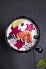 Fruits frais avec yaourt dans un bol à la surface sombre — Photo de stock