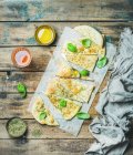 Homemade Italian focaccia flatbread cut into pieces with herbs, fresh basil leaves, olive oil in cup and glass of rose wine — Stock Photo