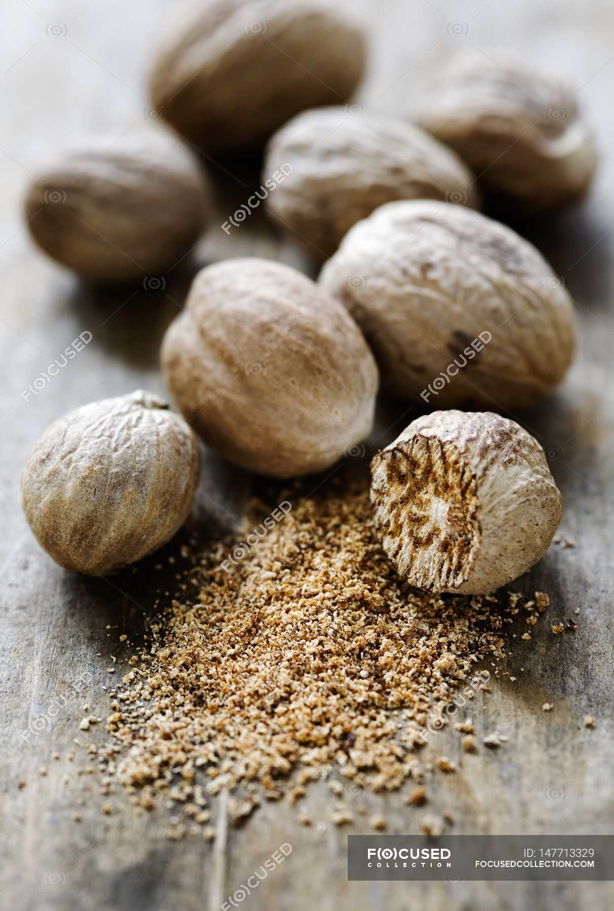 Whole and grated Nutmegs — nuts, raw Stock Photo 147713329