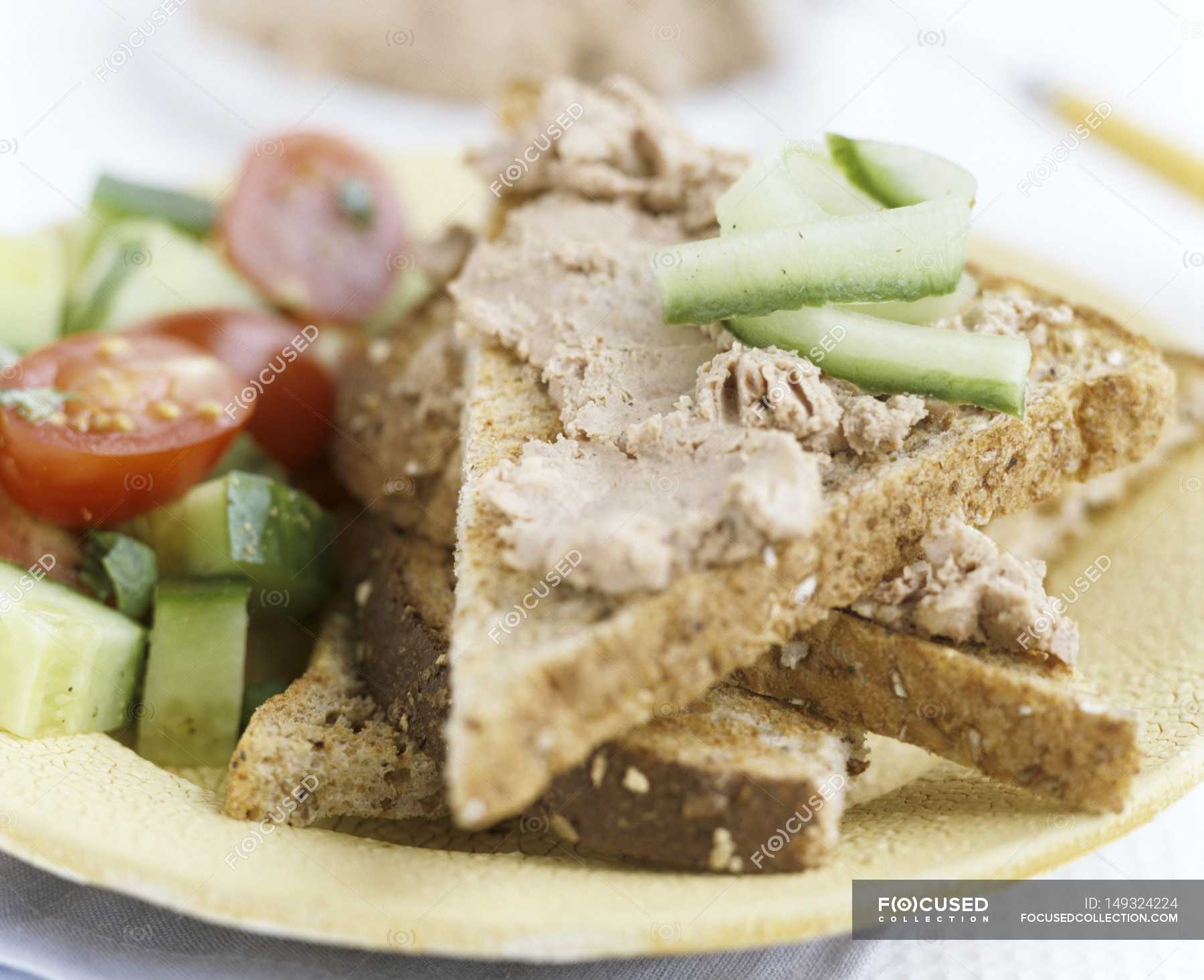 Closeup view of liver pate on toast triangles with vegetables