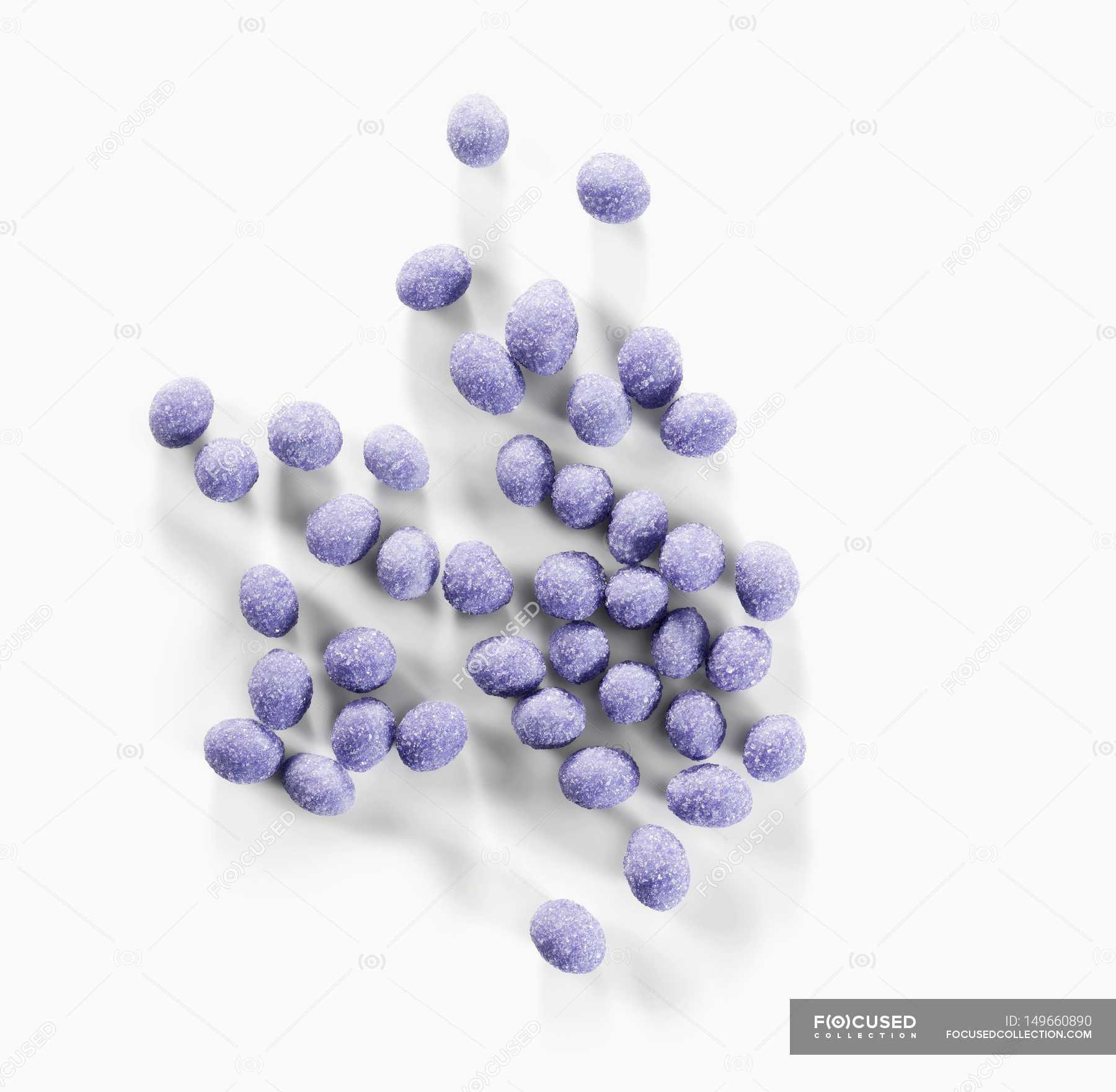 Closeup view of candied lavender flower balls on white surface 