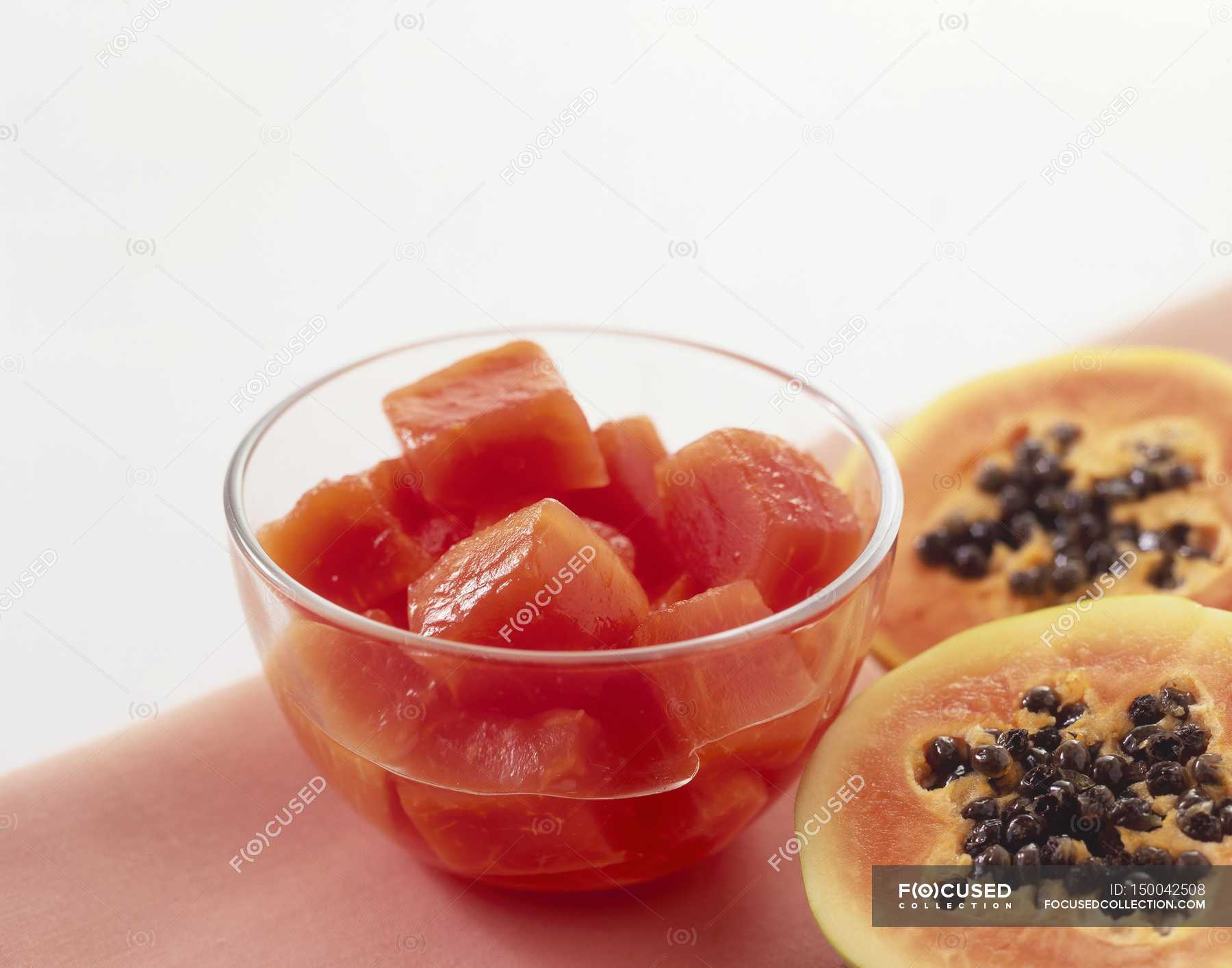 Closeup view of chunks of canned papaya in a bowl and halved fresh