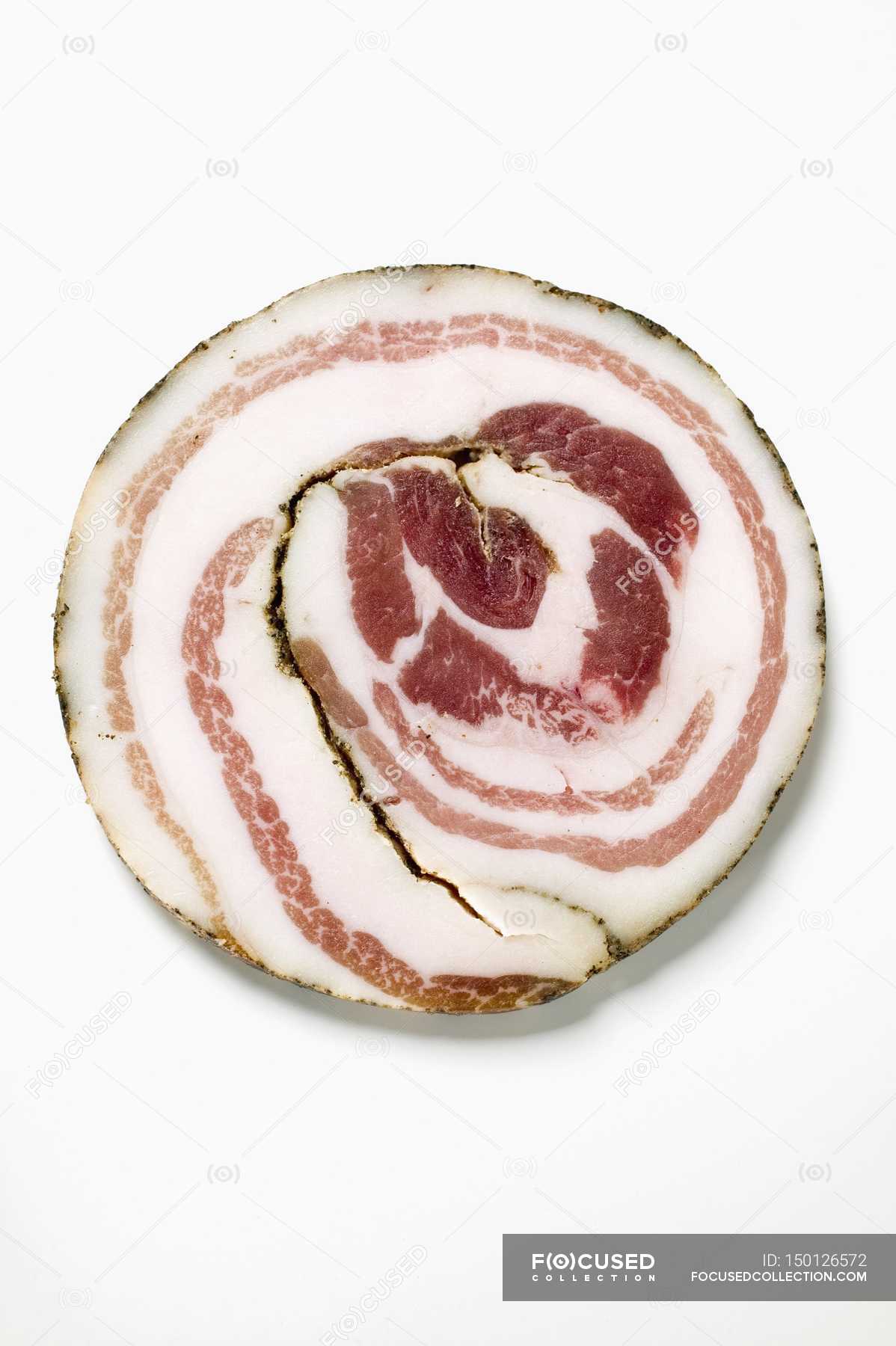 Closeup top view of one Pancetta slice on white surface — colors