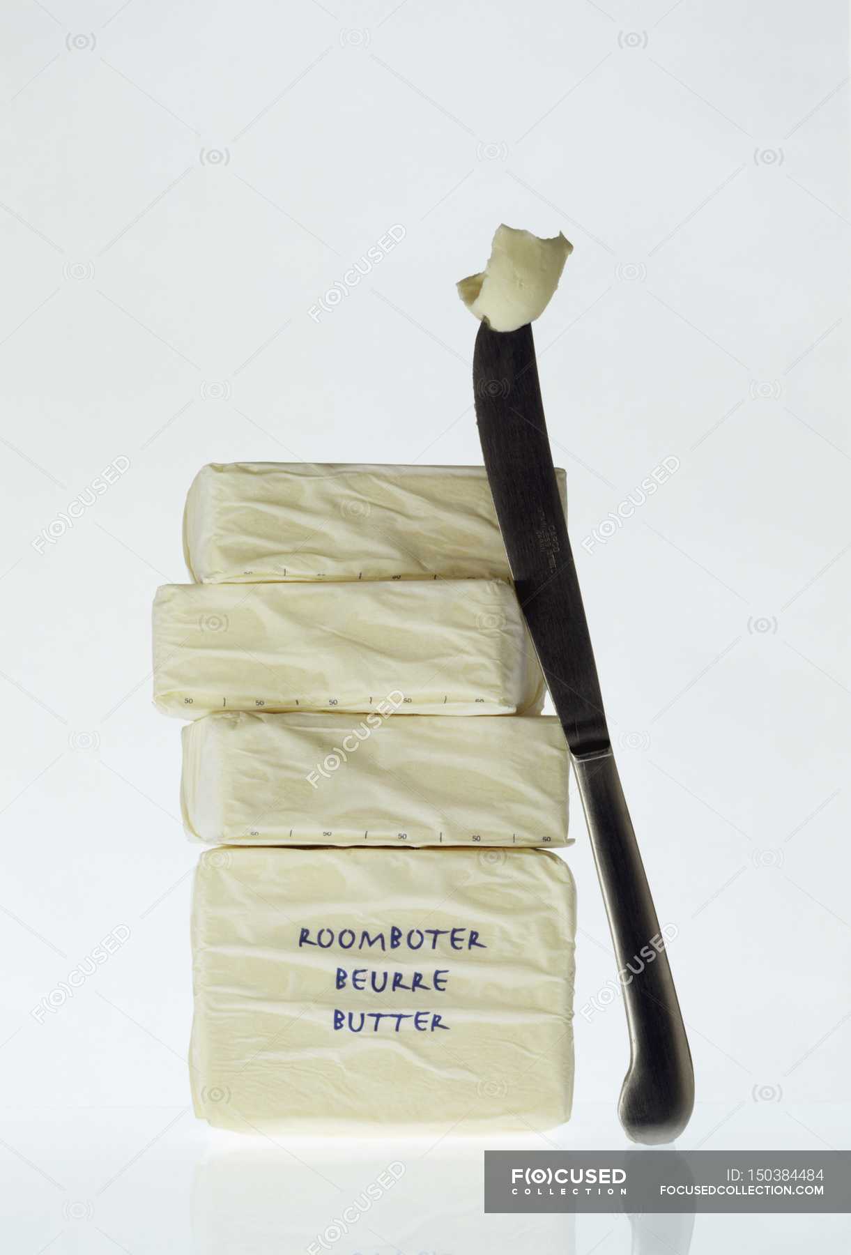 Closeup view of stacked blocks of butter with a knife — nutritious