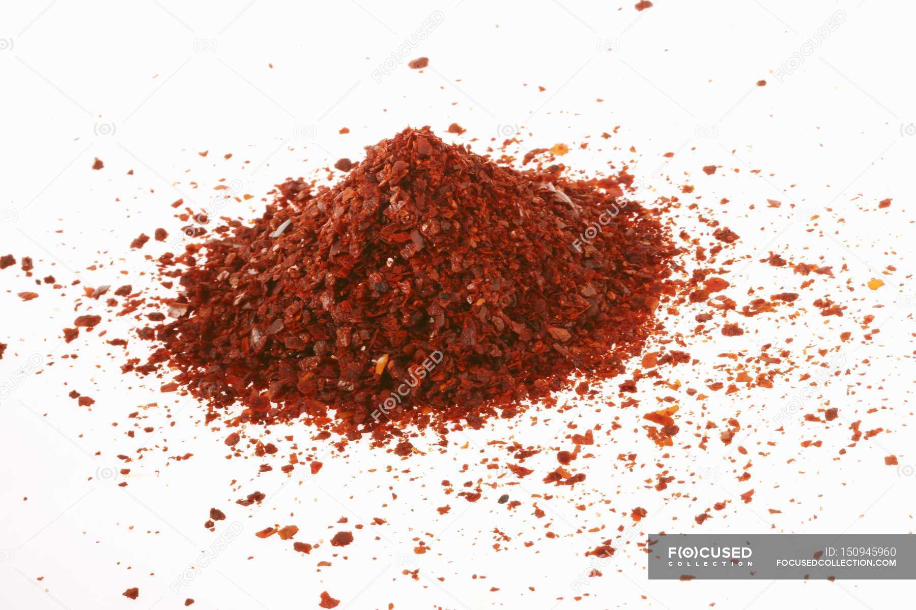 Closeup view of coarsely ground Chilli powder heap on white surface