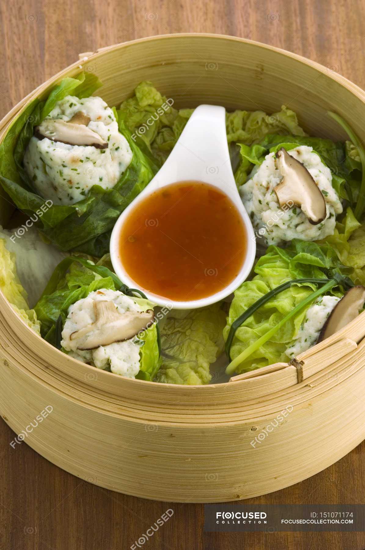 Elevated view of steamed fish dumplings with sauce in bamboo basket