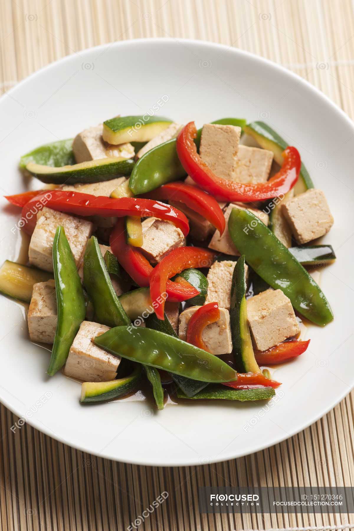 Stirfried tofu cubes and vegetables mange tout, courgette and red
