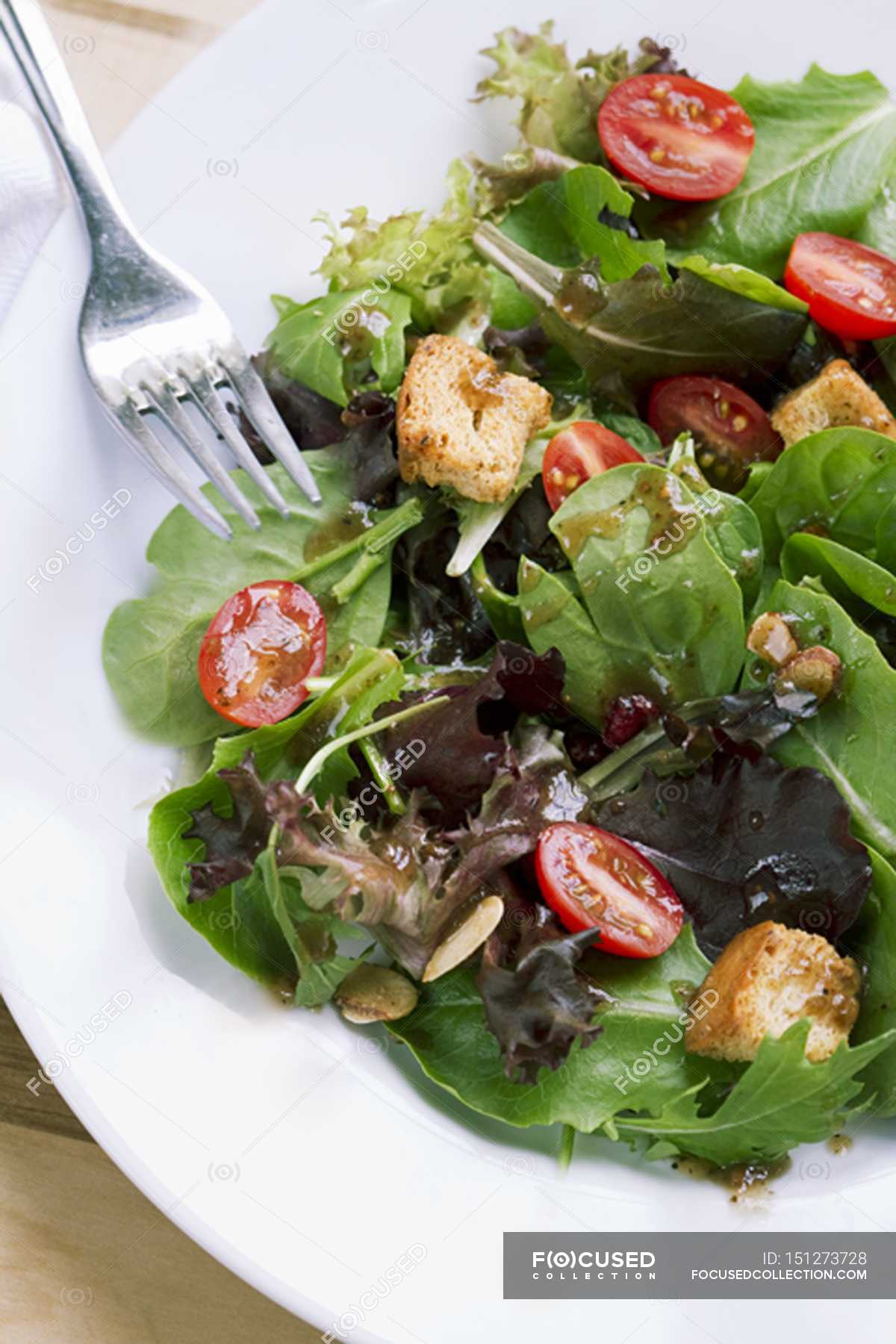 Spinach and Mixed Green Salad with Croutons and Tomatoes on white plate