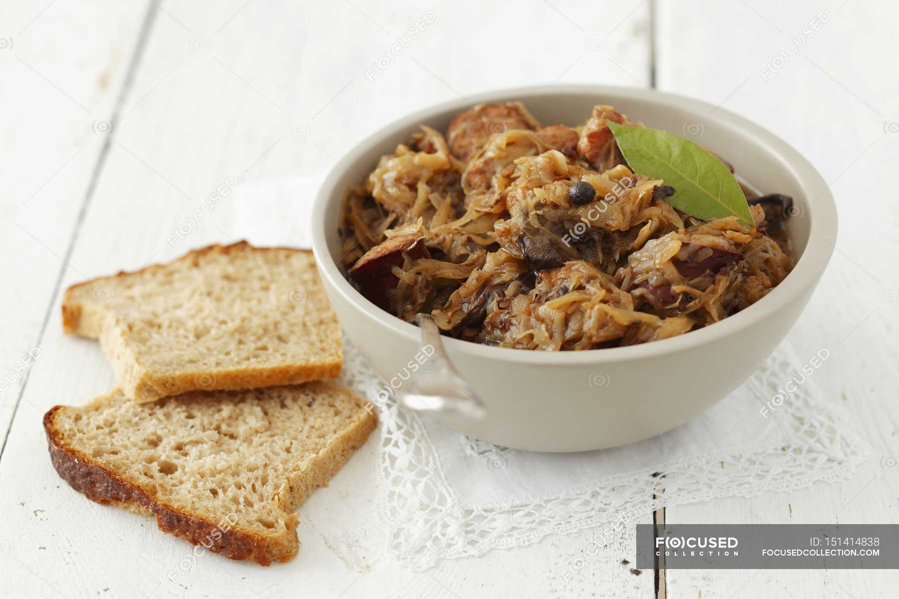 Bigos sauerkraut with sausage and bacon in white bowl on wooden