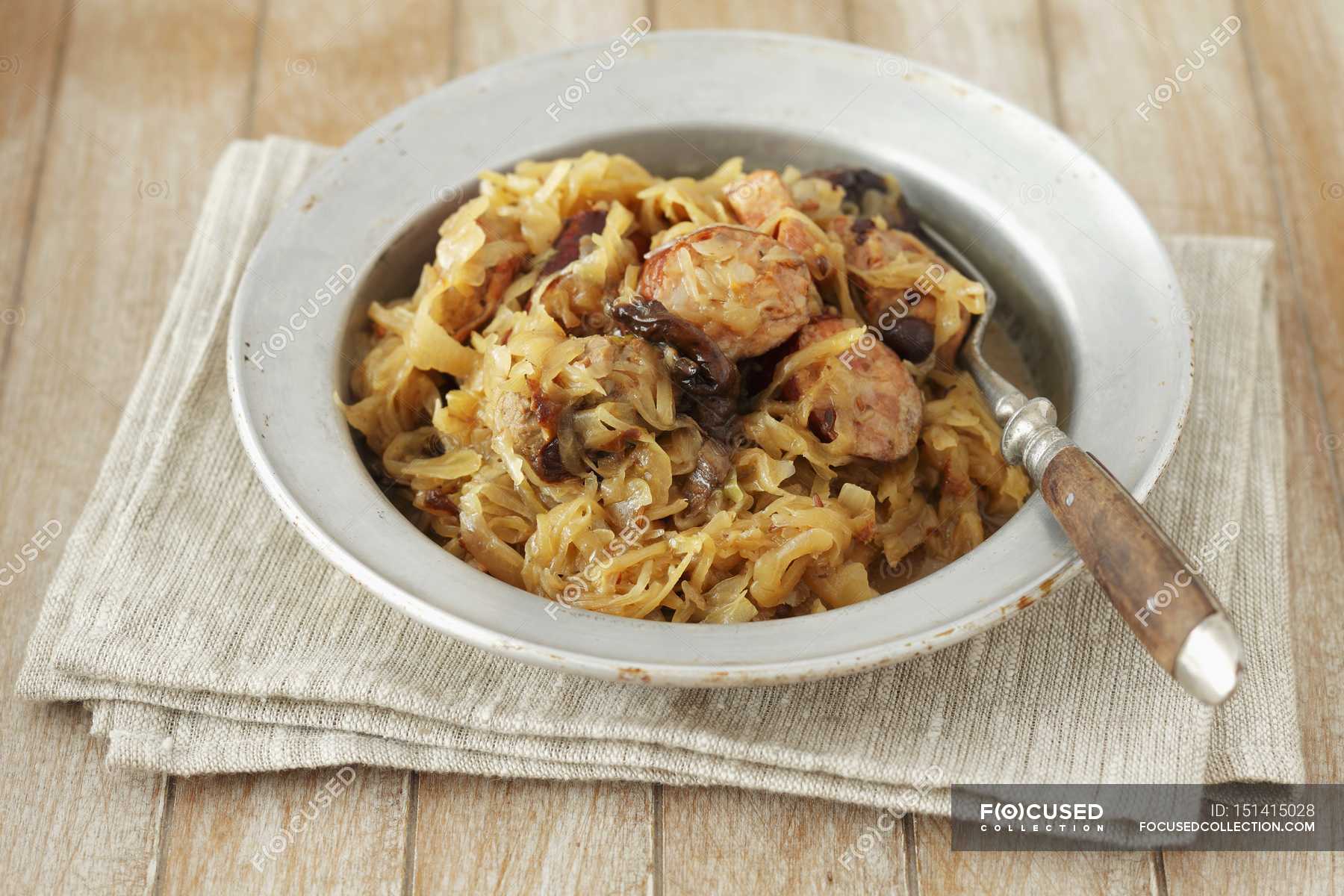 Bigos sauerkraut with sausage and bacon on white plate over towel