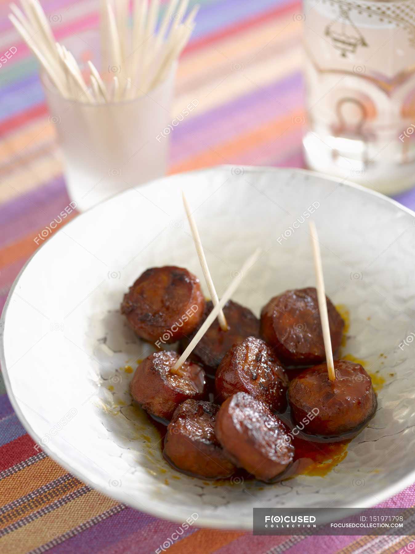 Closeup view of grilled Chorizo slices on sticks in white bowl — glass ...