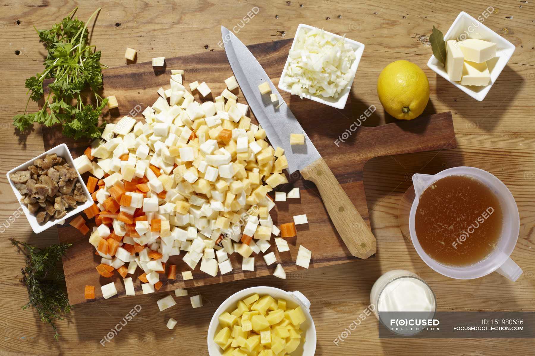 Ingredients for root vegetable soup on cutting board with knife over