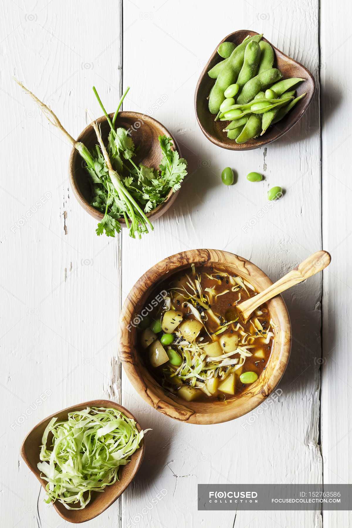 Miso soup with potatoes, white cabbage and soy beans over wooden