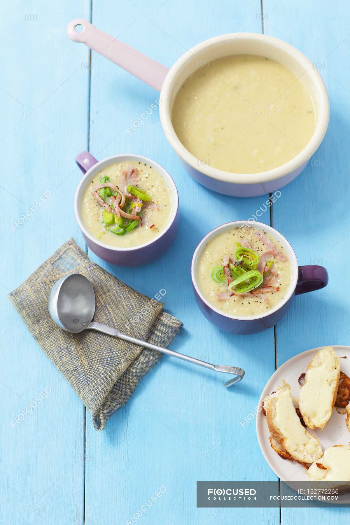 Cream of leek soup with ham over blue wooden surface — lifestyle