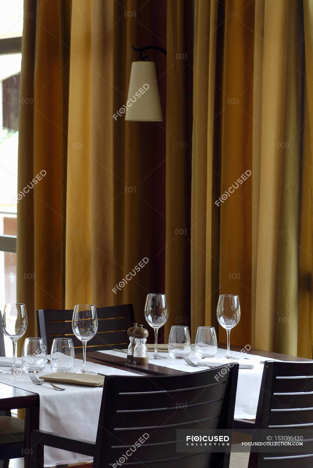 Laid table in a restaurant with curtains on a background — torch, natural  light - Stock Photo | #153086430