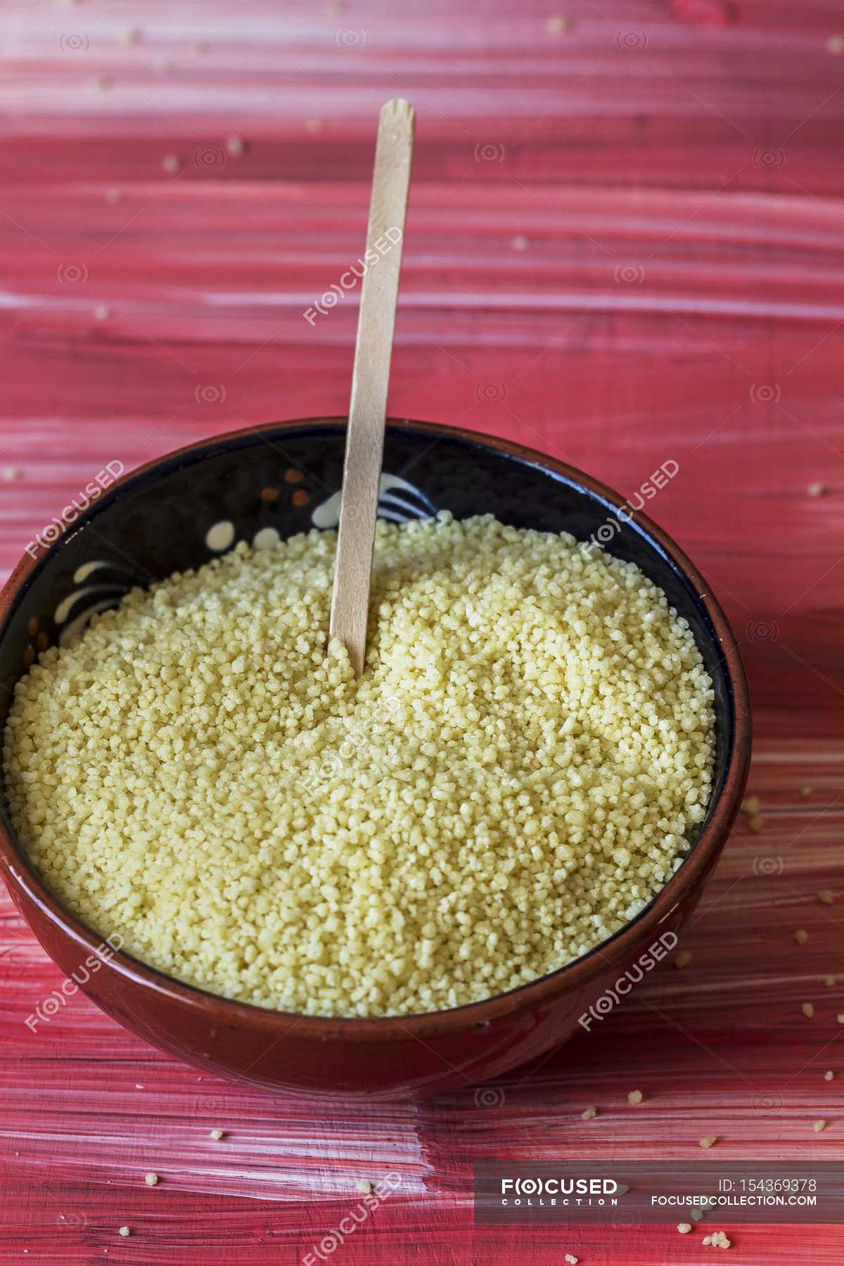 Raw couscous in bowl — cooking, garnish Stock Photo 154369378