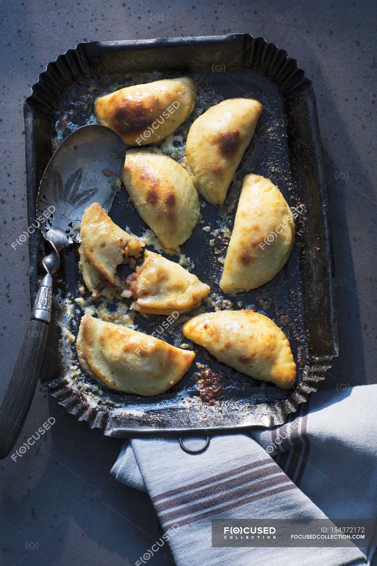 Top view of stuffed potato pastries with server on tray — colors, cloth
