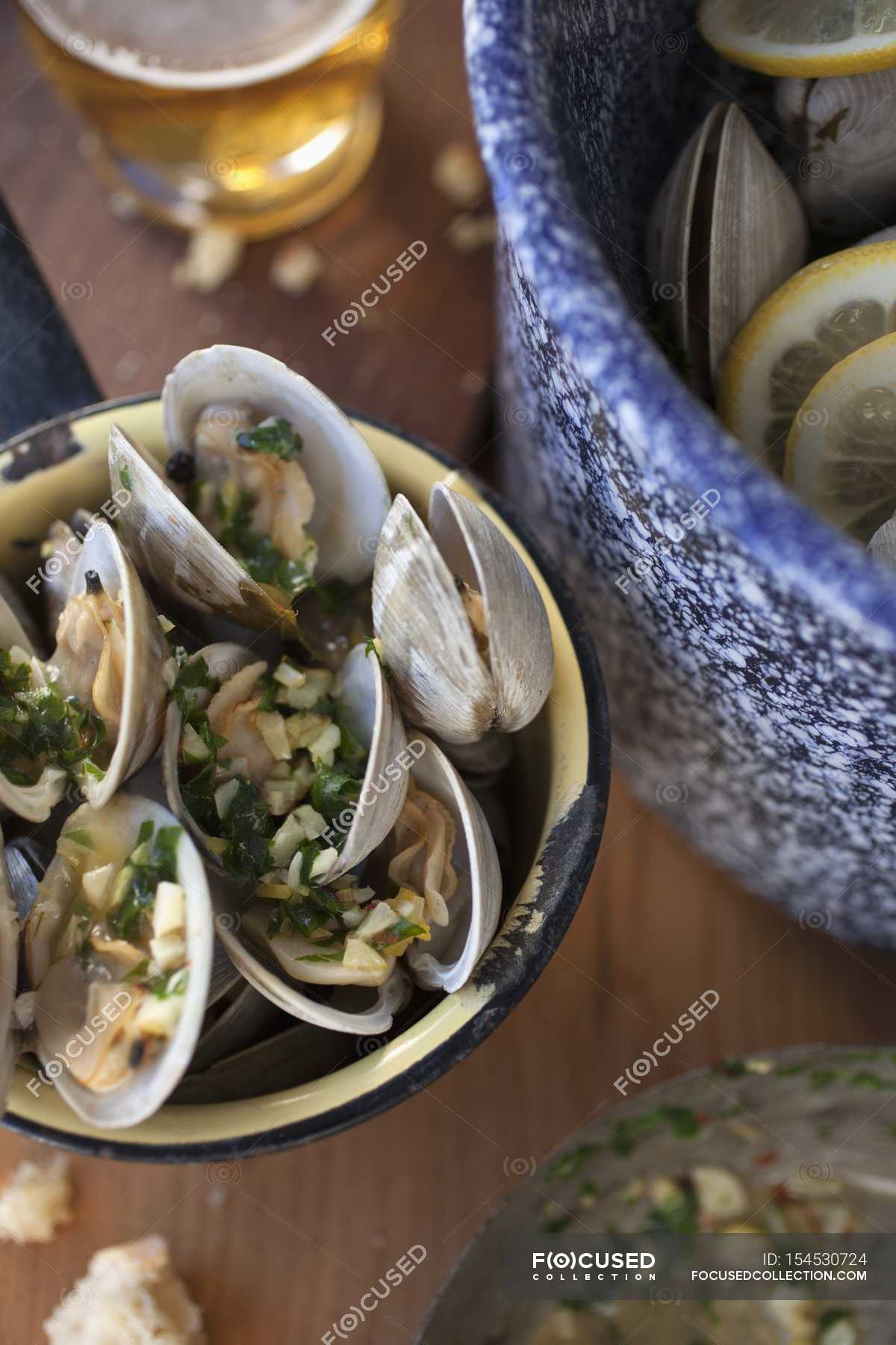 Steamed clams in a white wine broth with garlic and herbs on wooden ...