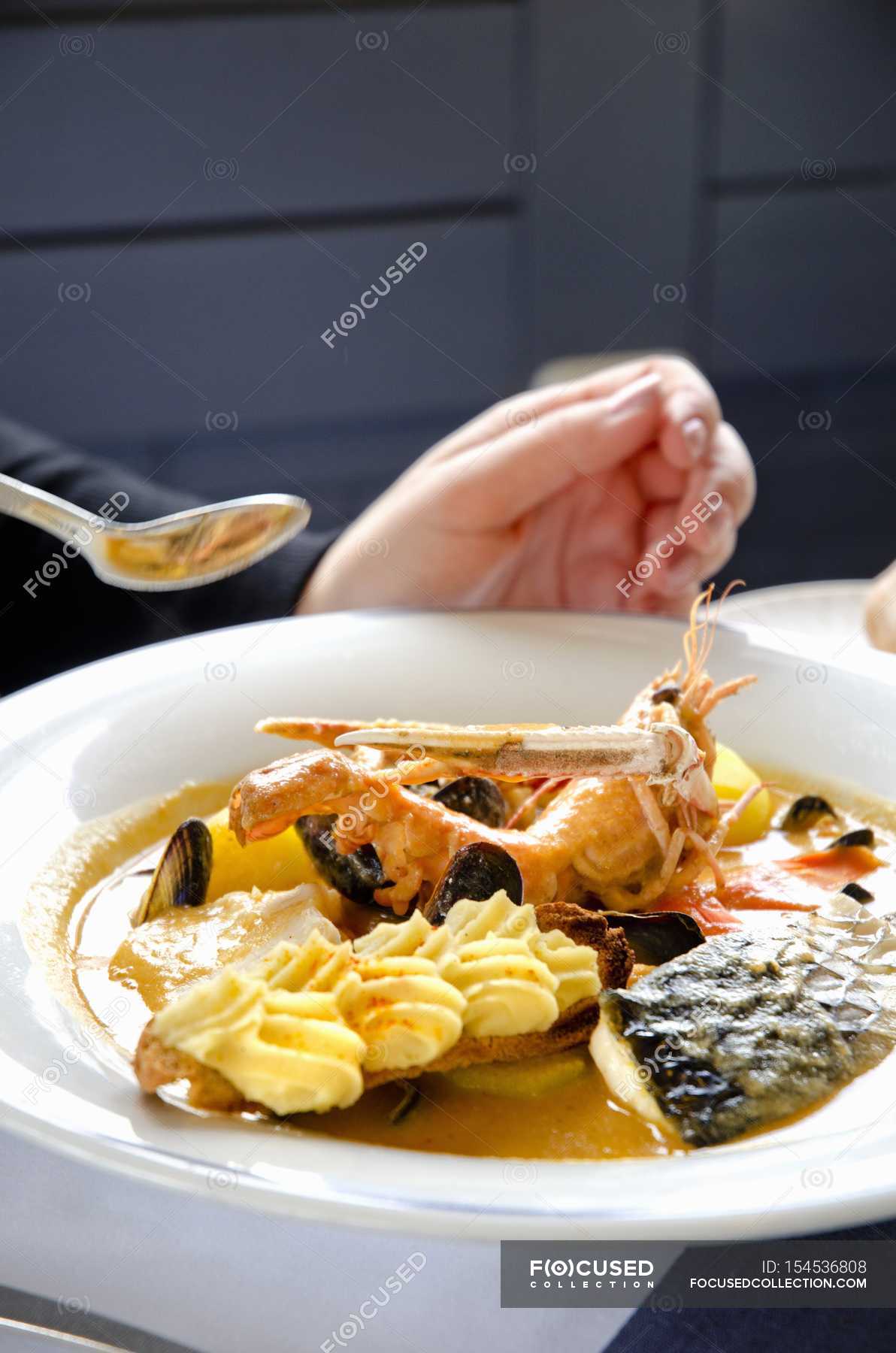 Closeup view of a person eating Bouillabaisse with fish and shrimp — diet,  details - Stock Photo | #154536808