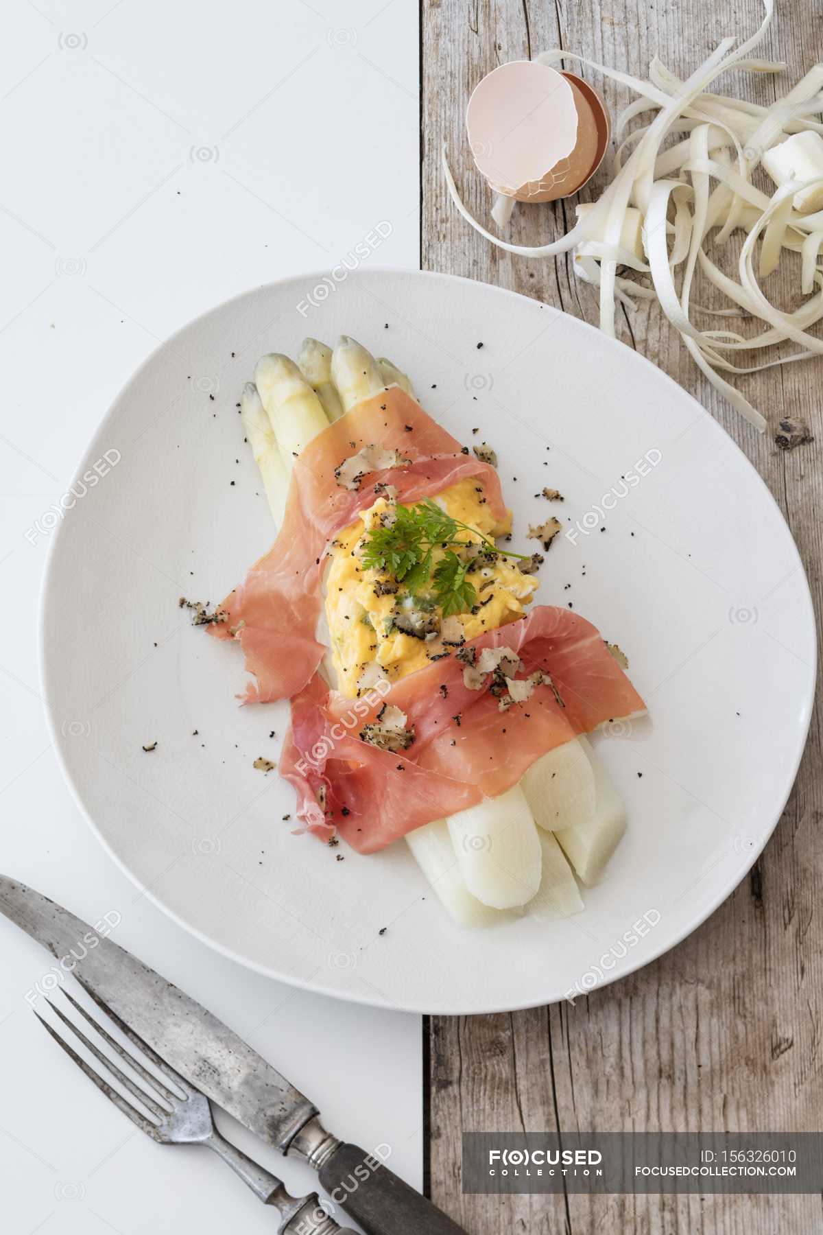 White asparagus with scrambled egg, Parma ham and truffles on white