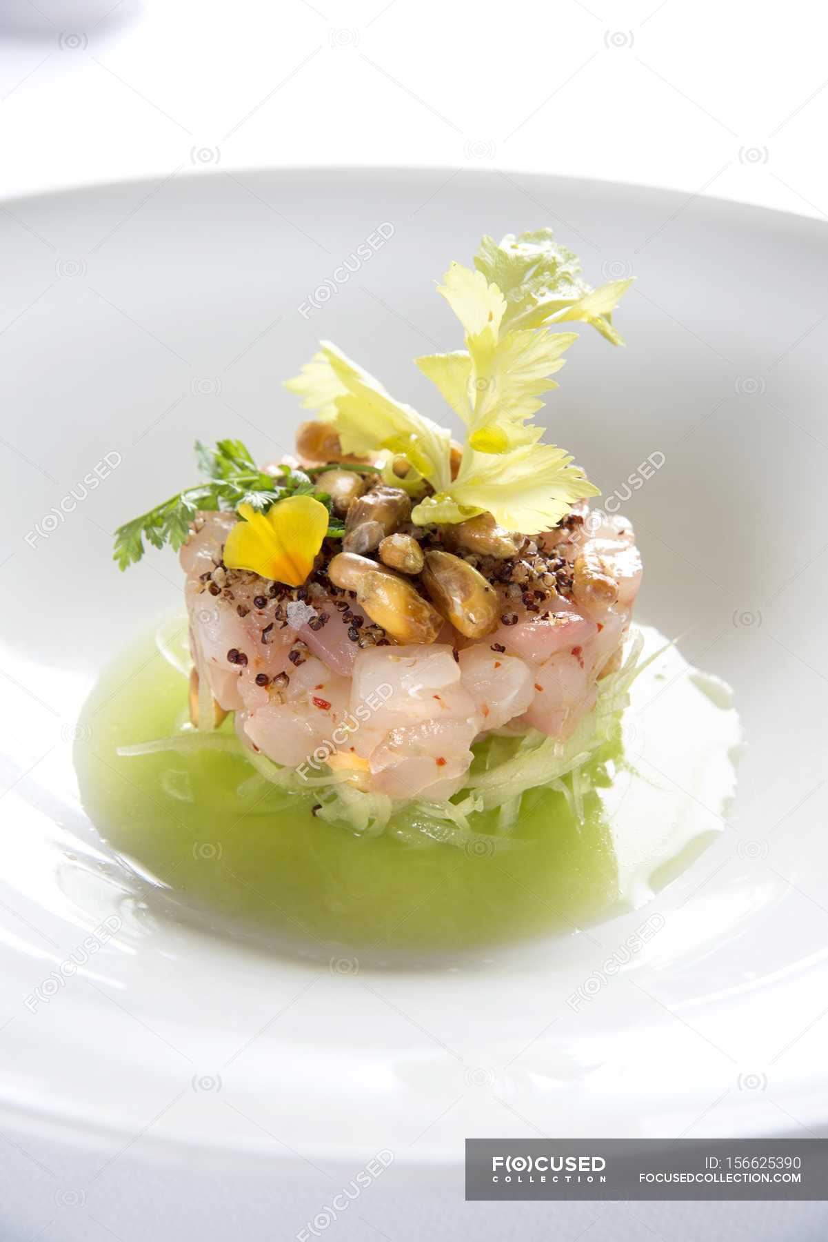 Tartare of yellowtail mackerel on julienned cucumber on white plate ...