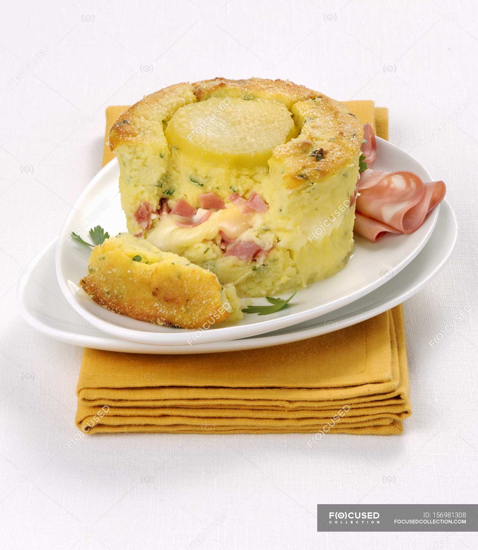 Italian potato flan with mortadella on white plate over towel — tasty