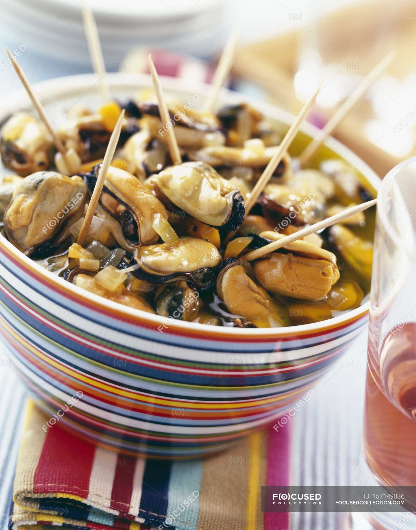 Mussels in escabeche marinade sauce in colored bowl over towel
