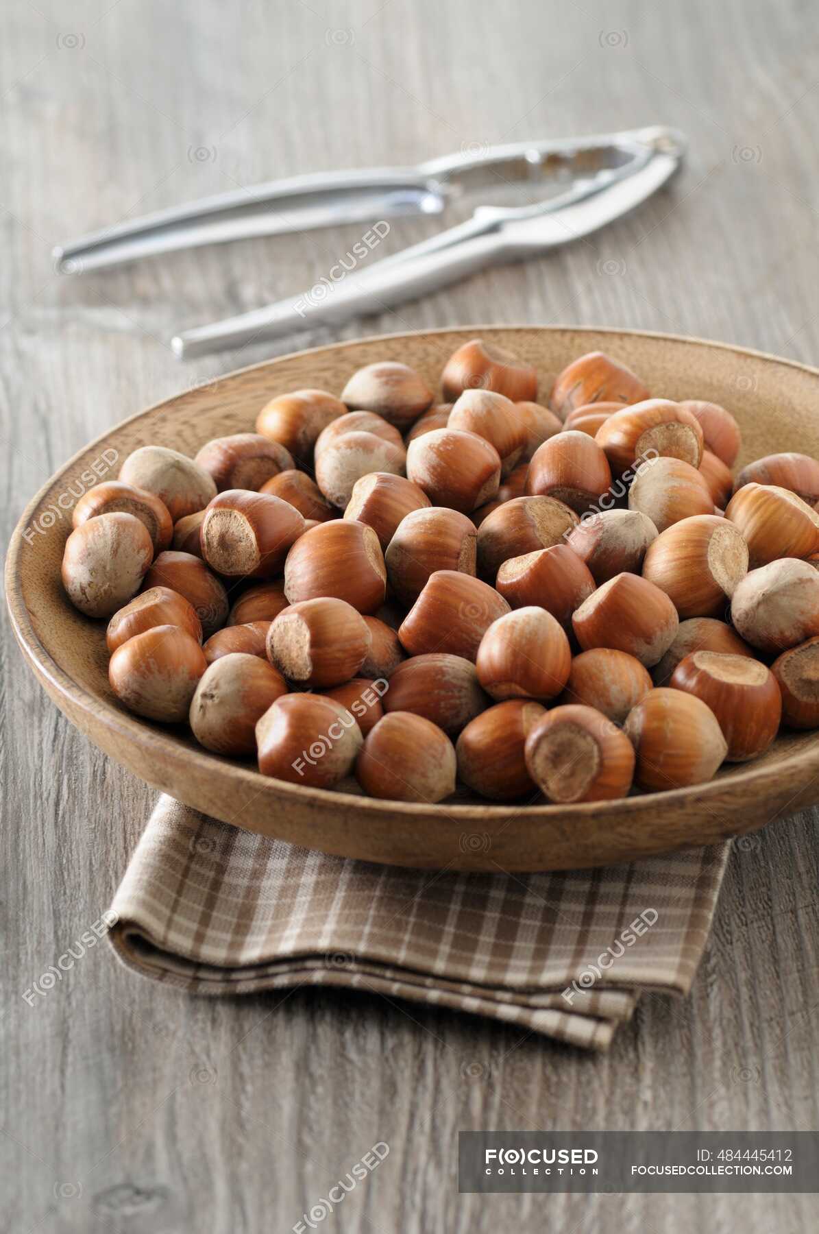 Hazelnuts in a wooden bowl with a nutcracker — whole, nut cracker